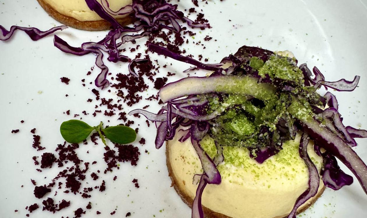 Dessert with purple cabbage and crumble on a white plate.