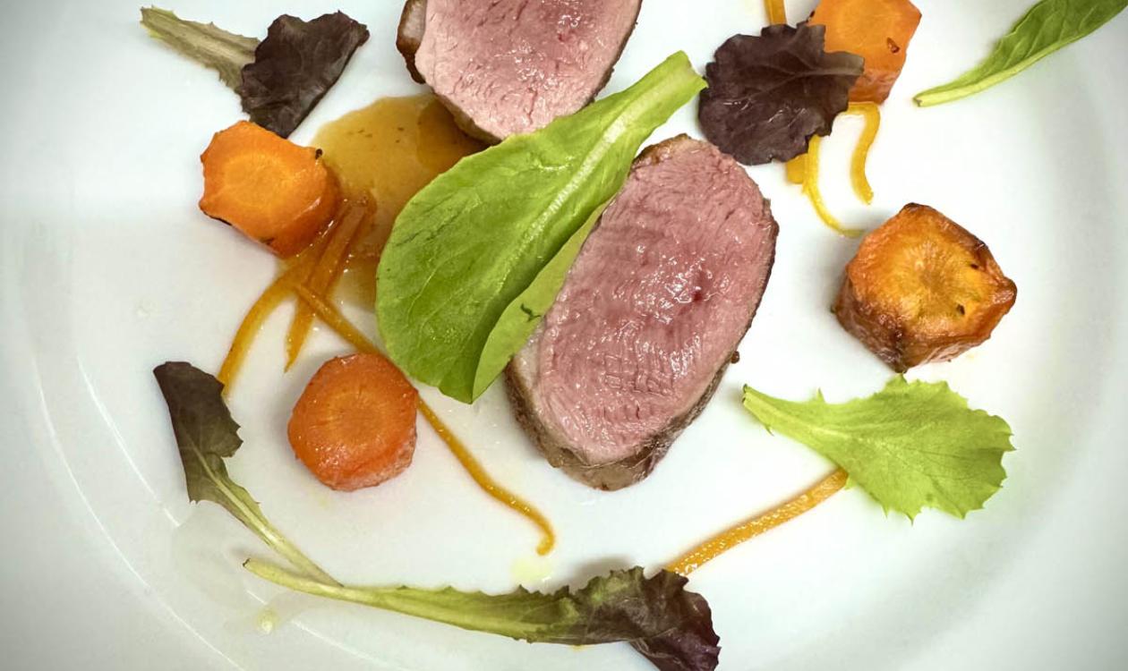 Filet with vegetables and leaves on a white plate.